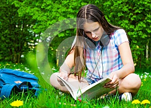 Student studying in park. Joyful happy teenager girl student sitting and reading outside on university campus