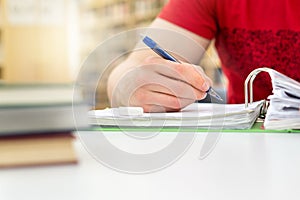 Student studying and writing notes in public or school library