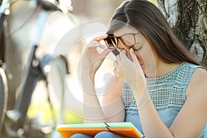 Student suffering eyestrain while is studying photo