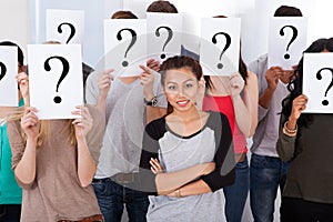 Student surrounded by classmates holding question mark signs photo