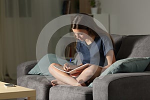 Student taking notes in the night at home