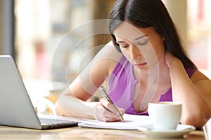Student taking notes using laptop in a terrace