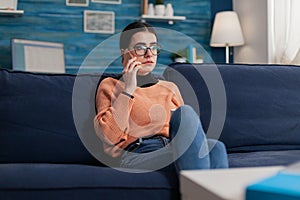 Student talking on the phone sitting on couch in living room.