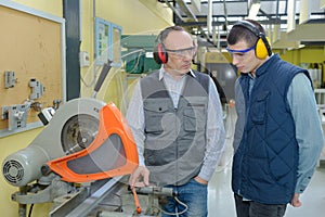 Student and teacher in carpentry class using circular saw
