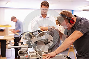 Student And Teacher In Carpentry Class Using Circular Saw