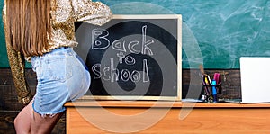 Student teacher mini skirt buttocks sit table blackboard inscription back to school. Girl denim skirt breaking