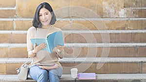 The student teen girl with education book and coffee cup sit on stai photo