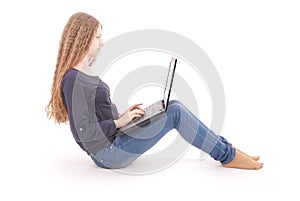 Student teenage girl sitting sideways on the floor with laptop