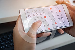 Student testing online learning, e-learning exam on smartphone with multiple choice questions by finger clicking.Concept