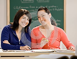 Student with text books doing homework with friend