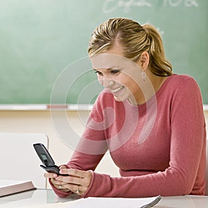 Student text messaging on cell phone in classroom photo