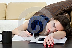 Student tired and sleeping in her living room over the notes.
