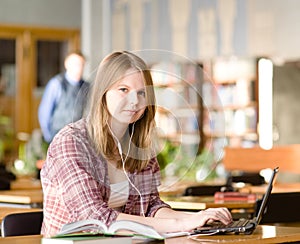Student using computer in a library. looking at camera
