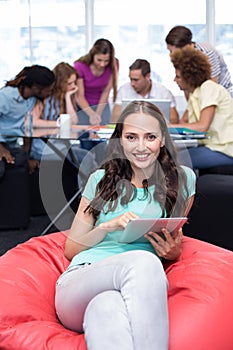 Student using digital tablet with friends in background