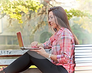 Student using laptop on park bench