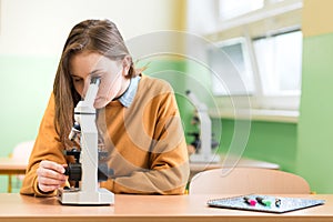 Student using microscope to examine samples in biology class.