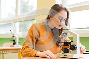 Student using microscope to examine samples in biology class.