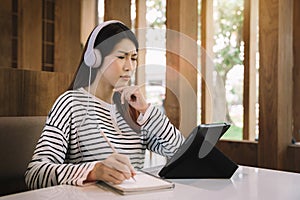 Student using tablet at cafe, women take notes in the notebook, online learning, internet marketing, working from home concept