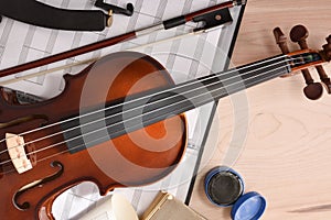Student violin and folder with staves on wooden table top