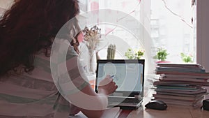 The student watches the lesson online and learns at home. A young girl does her homework while looking at the computer