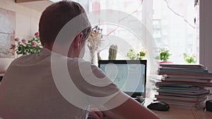 The student watches the lesson online and learns at home. A young guy does his homework while looking at the computer