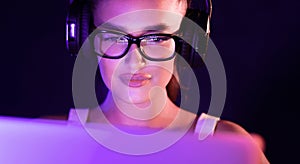 Student watching online tutorials, wearing headphones in the night