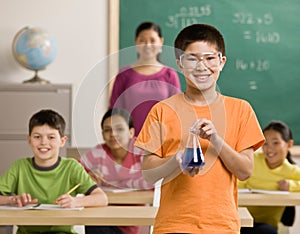 Student wearing goggles holds beaker of liquid