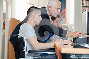 Student in wheelchair talking with classmate in library