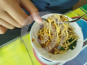 a student who is eating noodles bought in the canteen