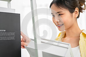 Student woman Asian holding a book in her hand and is selecting a treatise from the shelf to read.