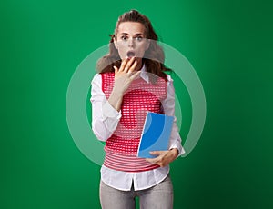 Student woman with blue notebook isolated on green background