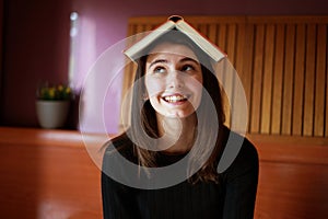 Student woman with a book on her head.