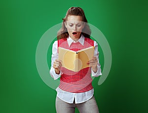 Student woman reading yellow book isolated on chalkboard green