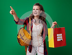 Student woman with shopping bag with books pointing at something