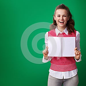 Student woman showing notebook blank page on green background