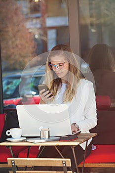 Student woman sit in cafe with laptop talk on smart phone , outd