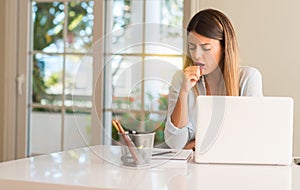 Young beautiful student woman with laptop at table, at home