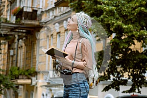 Student woman traveler with photo camera on her shoulder and history book.