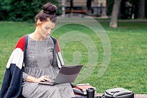 Student woman is using a laptop computer in the park