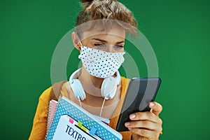 Student woman writing sms from smartphone isolated on green