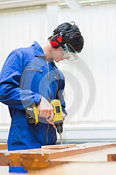 Student of a woodworking class drilling a hole