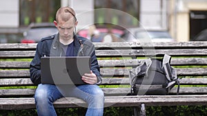 Student working remotely on laptop in city park