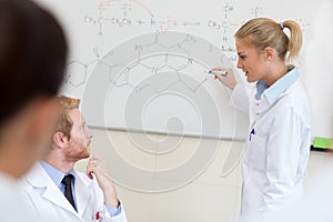 Student write chemical formula on blackboard