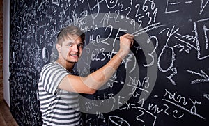 Student writing on big blackboard with mathematical symbols