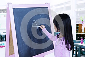 Student writing on blackboard in classroom