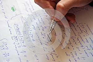 Student writing mathematical calculations on paper, closeup