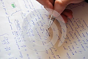 Student writing mathematical calculations on paper, closeup