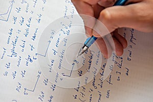 Student writing mathematical calculations on paper, closeup