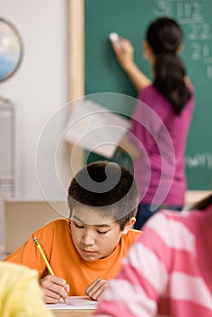 Student writing in notebook in school classroom photo