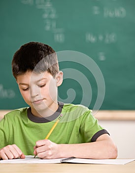 Student writing in notebook in school classroom